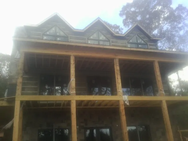Dormers and porch framing on a large log home under construction — Roof Coating work by our crew in Hustisford