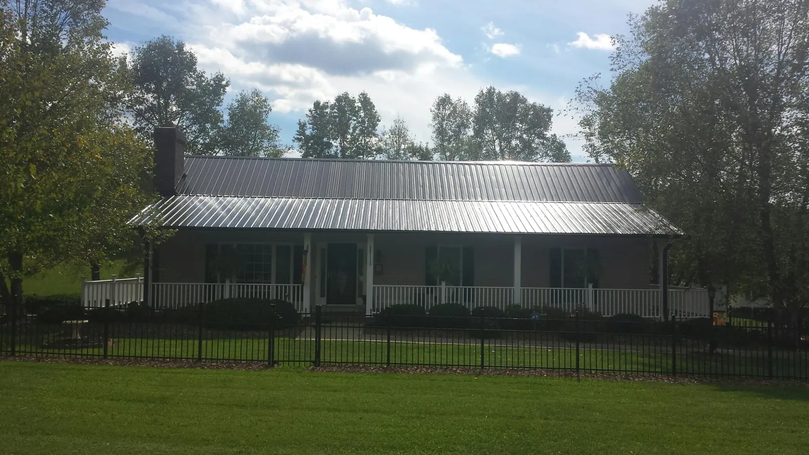 Gray metal roof on a brick ranch with a full width front porch — Gutter Guard Installation work by our crew in Hustisford