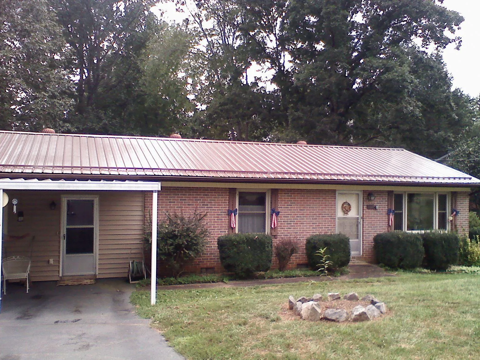 Bronze metal roof and carport on a brick ranch home — Roof Repair work by our crew in Hustisford