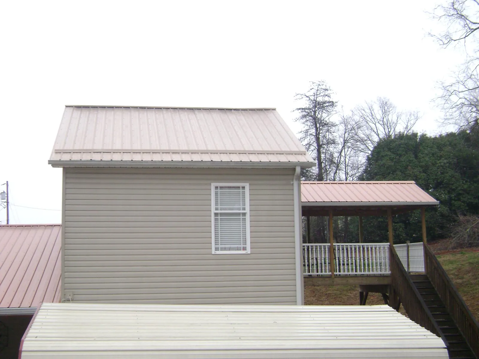 Tan metal roofs on a two story addition and attached porch, from a Roof Replacement job in Hustisford