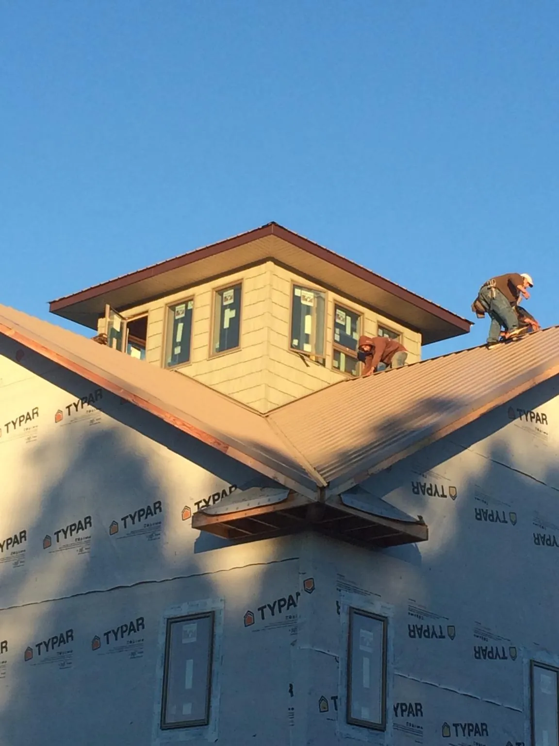 Roofers working around a rooftop cupola on a new metal roof at sunset — Roof Waterproofing in Hustisford by Roofing Brothers